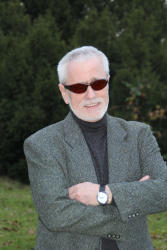 Harald Frase, Aufnahme bis zur Talie, Arme verschrenkt, hoch ziehende Augenbraue, verschmiztes Lächeln